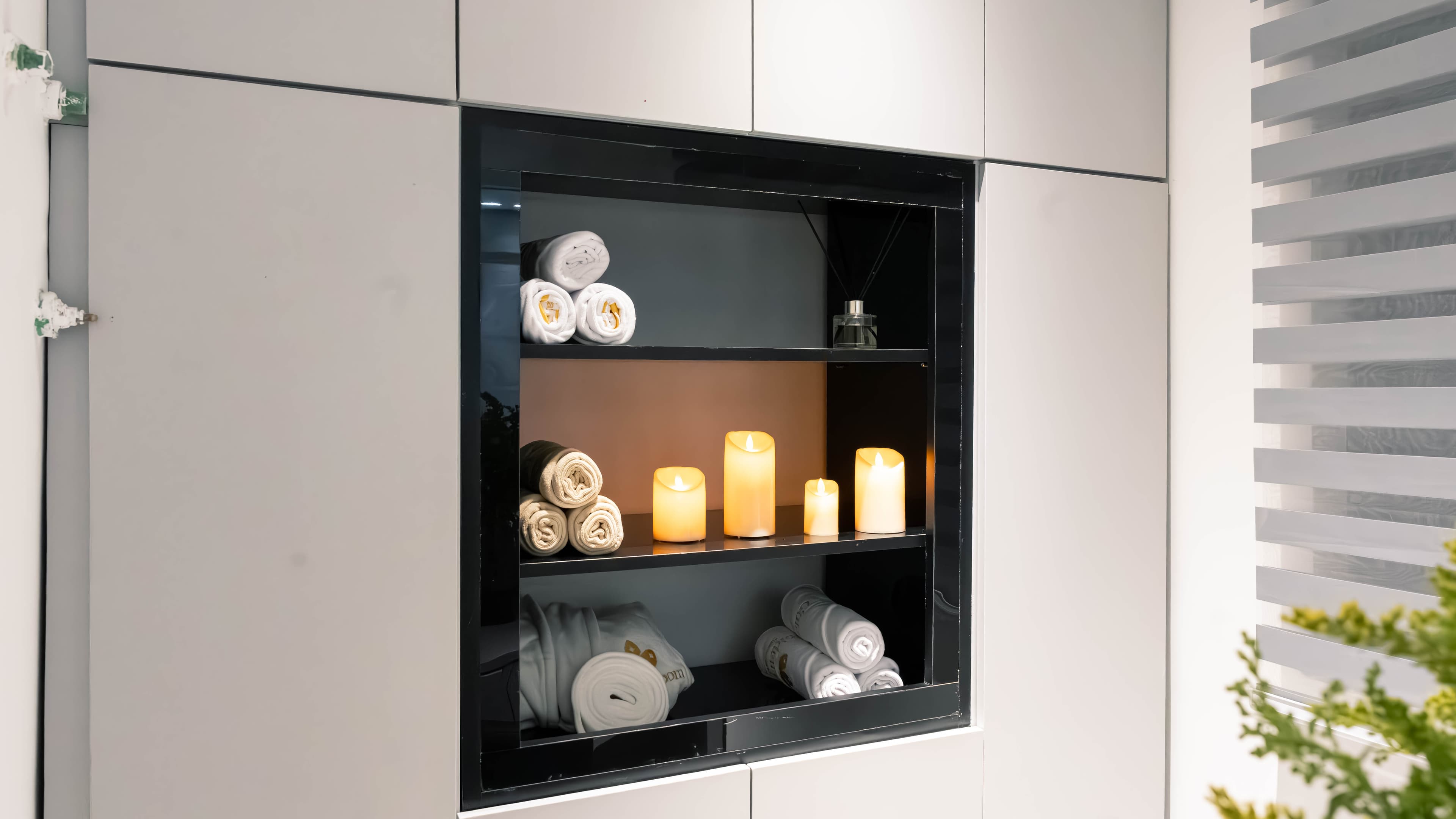 Towels and candles in a lit wall niche